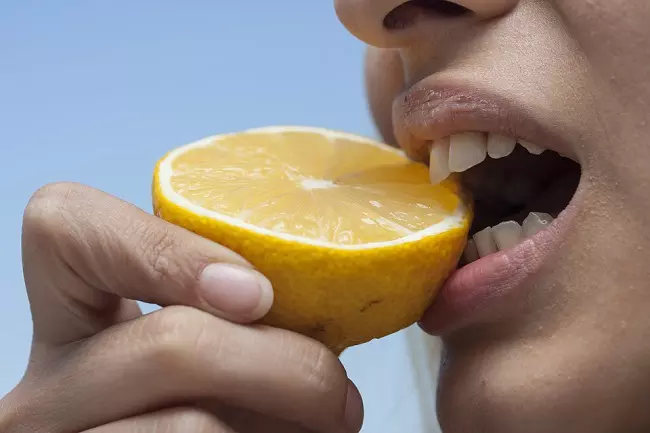 Woman eating lemon